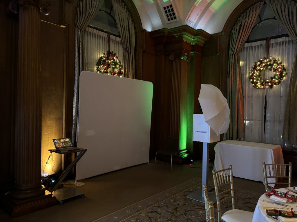 Corporate event uplighting in Vancouver with green and soft white LED accent lighting on venue columns near a photo booth screen.